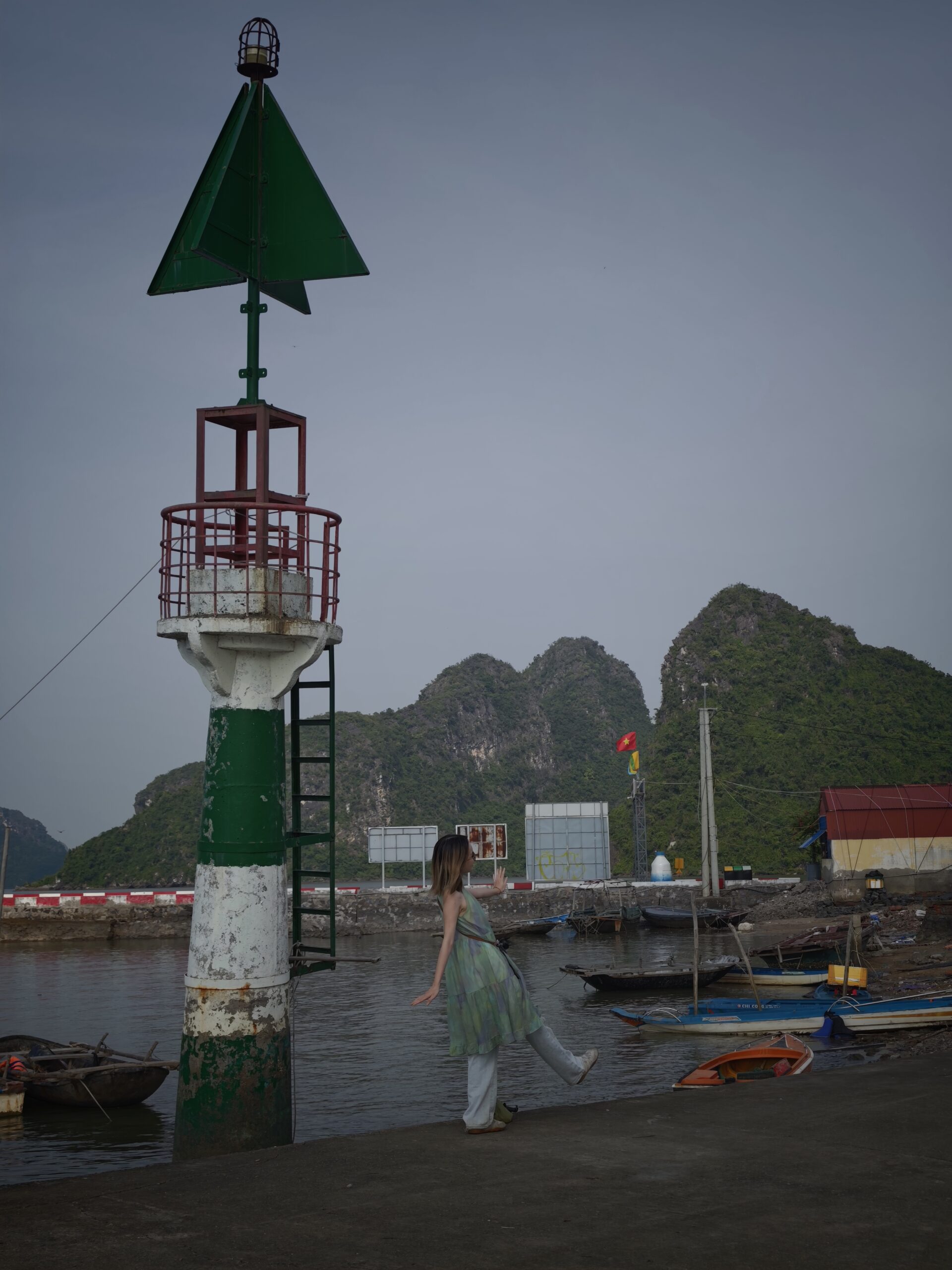 Small harbour lighthouse with boats and mountains behind