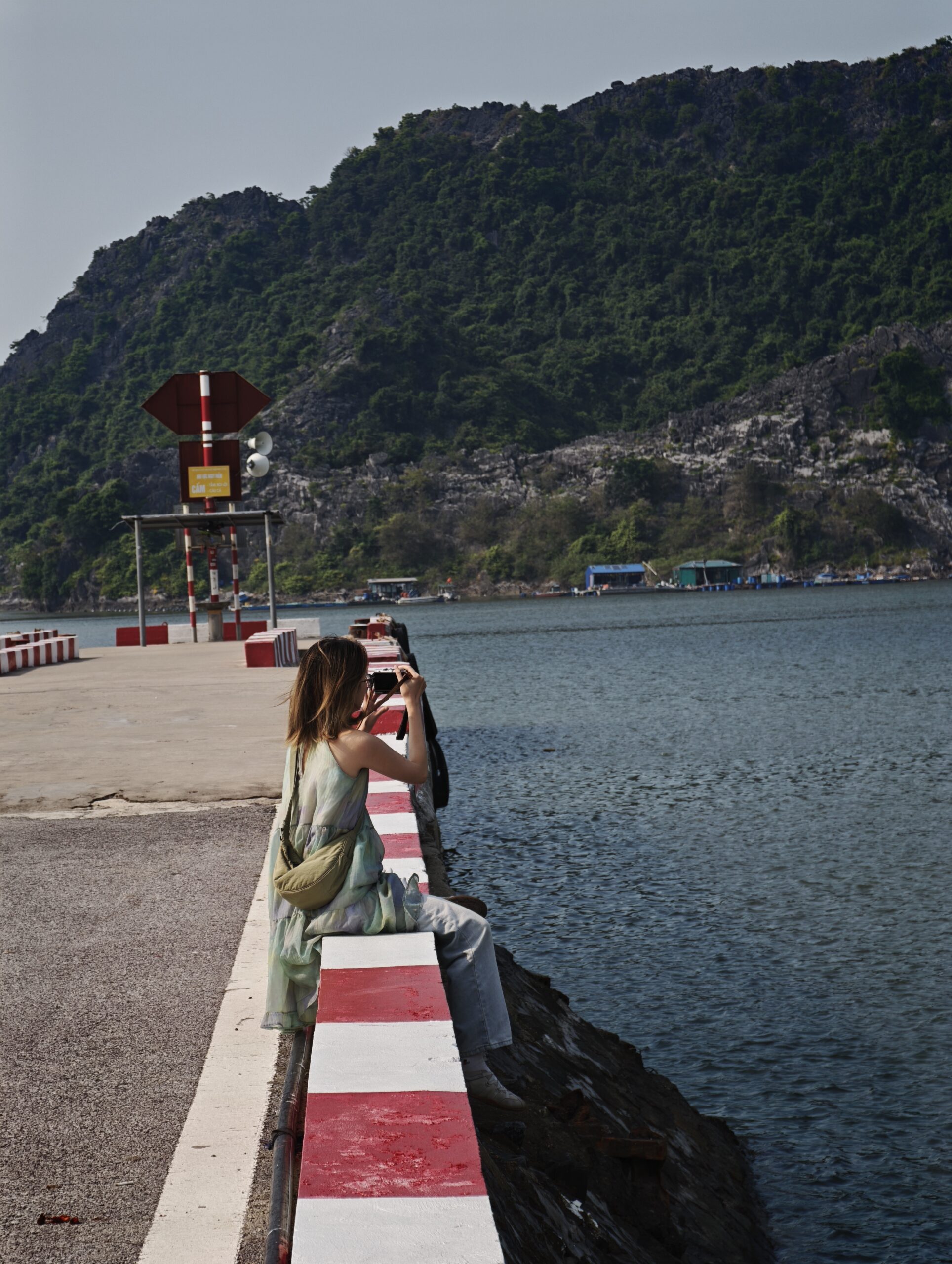 Traveler sitting by the Cát Bà pier facing the water