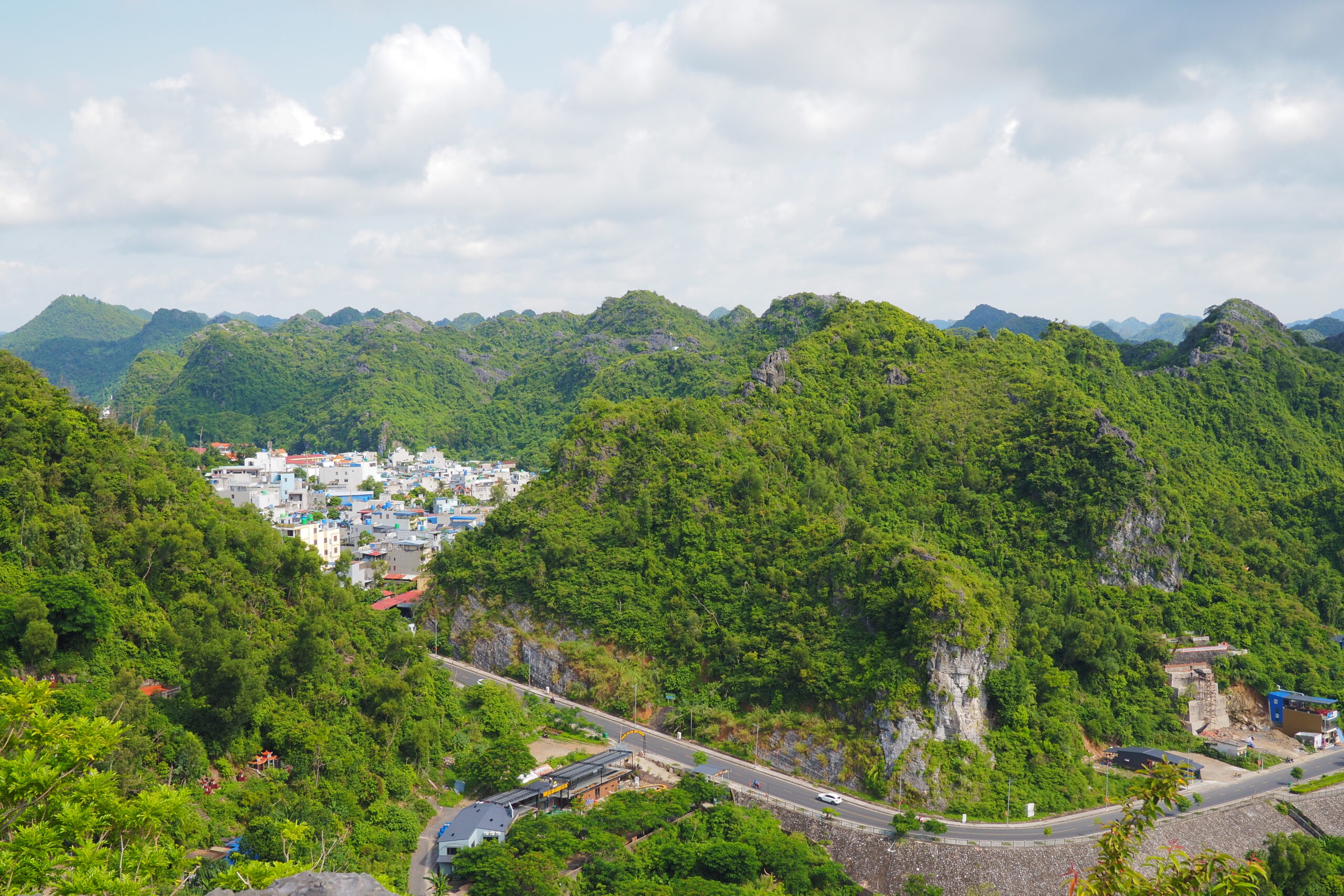 Green limestone mountains rising above Cát Bà town